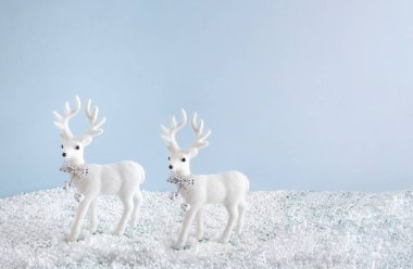 Karda beyaz geyikler. Mavi arka planlı yaratıcı kış mevsimi konsepti. Mutlu Noeller ve neşeli zaman kompozisyonu.
