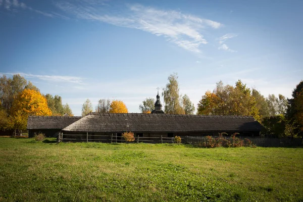 Une vieille cabane rustique en bois. En arrière-plan, il y a une église rustique en bois. — Photo