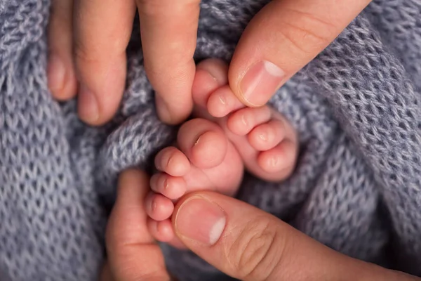 A szerető szülő puha szürke takaróban tartja a baba lábait. Boldog gyerekkort. Szülői felügyelet. A boldog család fogalma. — Stock Fotó