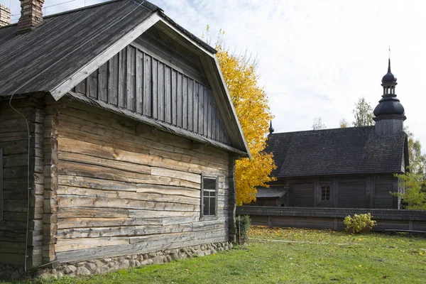 Une vieille cabane rustique en bois. En arrière-plan, il y a une église rustique en bois. — Photo