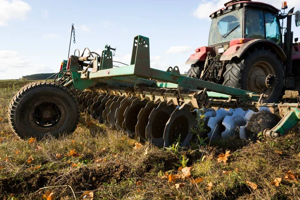 Rolnik w ciągniku, maszyny rolnicze, przygotowuje grunt z kultywatorem. Nowoczesny czerwony traktor na polu. Pług ciężkiego ciągnika podczas uprawy roli na polu z pługiem. — Zdjęcie stockowe