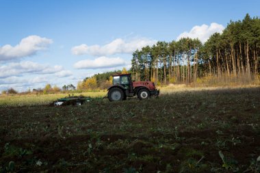 Traktörlü bir çiftçi, tarım makineleri, toprağı ekiciyle hazırlıyor. Tarlada modern bir kırmızı traktör. Bir tarlada tarla sürerken ağır bir traktörü sürmek..
