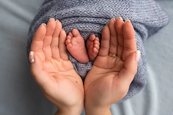 Bacaklar, ayak parmakları, ayaklar ve yeni doğmuş bir bebeğin topukları. Anne babanın elleriyle, baba, anne çocuğun bacaklarını nazikçe tutuyor.. — Stok fotoğraf