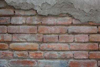Eski, eski tuğla duvar dokusunun kırmızı arkaplanı. Alçı ve duvar harcı izleri olan eski bir taş duvarın yakın görüntüsü..