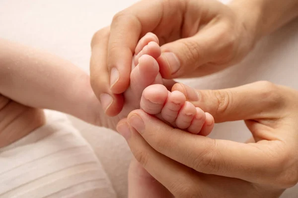 Pappans handflator, mamman håller i det nyfödda barnets fot. Fötter av den nyfödda på handflatorna av föräldrarna. Studiofotografering av en barntår, klackar och fötter. — Stockfoto