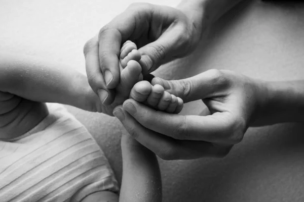 父亲的手掌，母亲抱着新生婴儿的脚。新生儿的脚踏在父母的手掌上。小孩的脚趾，脚跟和脚的摄影棚。黑人和白人. — 图库照片