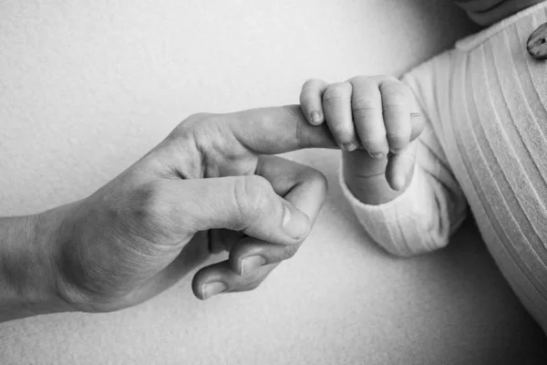 Novorozenec má po porodu pevný stisk na prstu rodičů. Zblízka malá ručička dítěte a dlaně matky a otce. Pojem rodičovství, péče o děti a zdravotní péče. Černobílá fotografie. — Stock fotografie