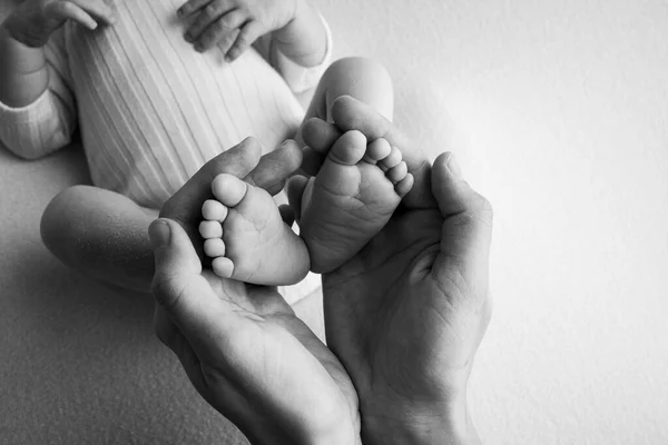 Долоні батька, мати тримає ногу новонародженої дитини. Ноги новонародженого на долонях батьків. Студійна фотографія дитячих пальців ніг, п'ят і ніг. Чорно-білий . — стокове фото