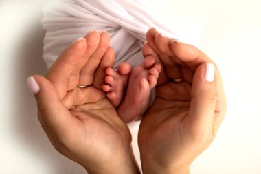 Baba 'nın avuç içi, anne yeni doğan bebeğin ayağını tutuyor. Yeni doğan bebeğin ayakları, ebeveynlerin avuçlarında. Stüdyo fotoğrafçılığı. Ayak, ayak ve ayak parmakları.. 