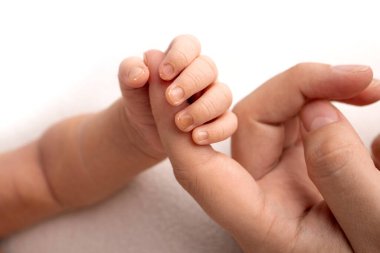 Beyaz bir bebek doğumdan sonra ebeveynlerin parmaklarını sıkıca kavrıyor. Çocuğun küçük eli ve anne ve babanın avuç içi. Ebeveynlik, çocuk bakımı ve sağlık konsepti. 