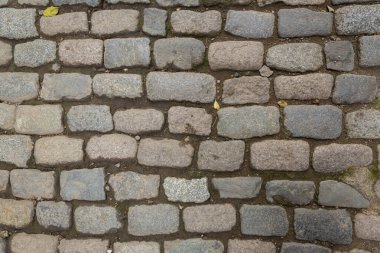 Paving stones from granite. The stones are gray and red. Old stone roads.