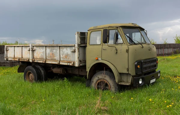 An old lorry in a field among the green grass. Military cabin color. Rusty body. — Stock Photo, Image