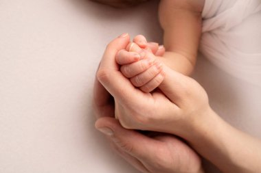 Anne ve babanın elinde uyuyan yeni doğmuş bir bebeğin eli. Yeni doğmuş bir bebeğin minik parmakları. Aile el ele tutuşuyor. Stüdyo makro fotoğrafçılık. Aile ve aşk kavramları.