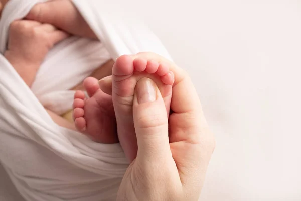 Mamma masserar sin bebisfot. Närbild bebis fötter i mor händer. Förebyggande av platta fötter, utveckling, muskeltonus, dysplasi. Familje-, kärleks-, omsorgs- och hälsobegrepp. Studiomakro. — Stockfoto