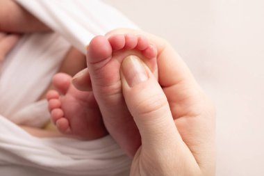 Anne bebek ayağına masaj yapıyor. Bebek ayaklarını annenin ellerine teslim et. Düz taban, gelişim, kas yapısı, displazi. Aile, sevgi, ilgi ve sağlık kavramları. Stüdyo makrosu.