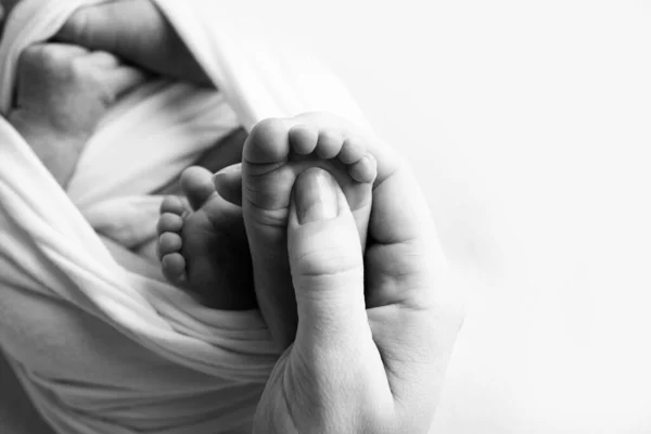 Moeder doet massage op haar baby voet. Close-up babyvoeten in moederhanden. Preventie van platte voeten, ontwikkeling, spiertonus, dysplasie. Familie, liefde, zorg, gezondheidsconcepten. Zwarte en witte macro. — Stockfoto