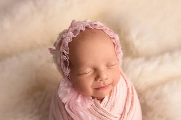 Спящая новорожденная девочка в первые дни жизни в розовом коконе с розовой кепкой на белом фоне. Студийная макрофотография, портрет новорожденного ребенка. Понятие женского счастья. — стоковое фото