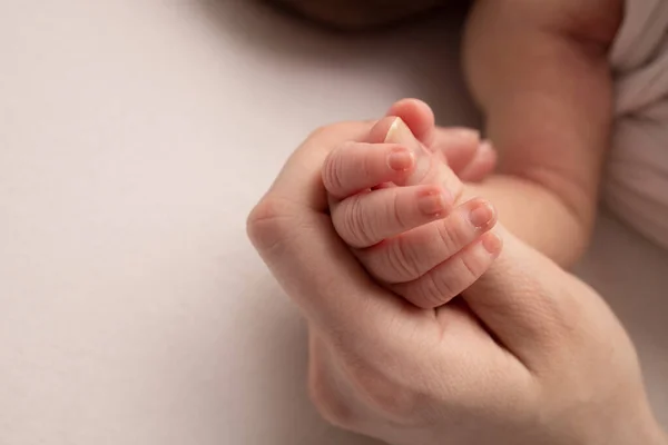 La mano de un recién nacido dormido en la mano de la madre y el padre de cerca. Dedos pequeños de un recién nacido. La familia está cogida de la mano. Estudio macro fotografía. Conceptos de familia y amor. — Foto de Stock