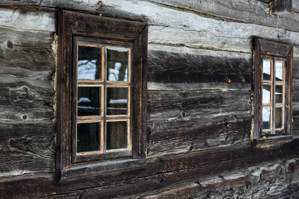 Casa de madeira rústica feita de troncos redondos. Aldeias abandonadas e casas. Projeto antigo da janela. Quadro de janela de madeira. Uma aldeia coberta de neve. Edifícios antigos. Fotografia profissional. — Fotografia de Stock