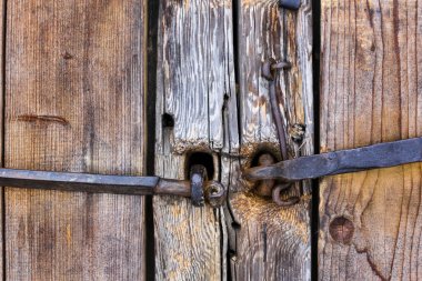 Eski bir ev. Kapılar, kapılar. Dövülmüş metal kapı kolları, sürgüler, menteşeler, kancalar. Sefil ağaç, eski ahşap yapı..