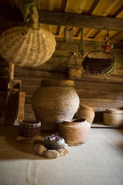 Eski bir ahşap kulübe ve yuvarlak kütüklerden yapılmış bir ahır. İç dekorasyon. Fıçılar, tencereler, dökme demir kaplar, hasır sepetler, dönen tekerlekler ve çarklar..