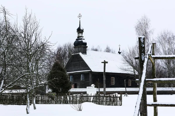 丸い丸太で作られた古い木造教会。ドームを横切れ。冬のロシアの風景。雪に覆われた木。雪に覆われた古いロシアの村を放棄 — ストック写真