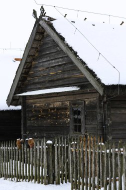 Eski ahşap bir kulübe, sazdan çatılı ahşap bir ev. Karla kaplı terk edilmiş bir Rus köyü. Ahşap çitli ahşap bir ahır..