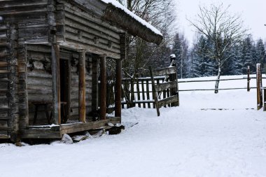 Rus kışı manzarası. Eski ahşap bir kulübe, sazdan çatılı ahşap bir ev. Karla kaplı terk edilmiş bir Rus köyü. Ahşap çitli ahşap bir ahır..