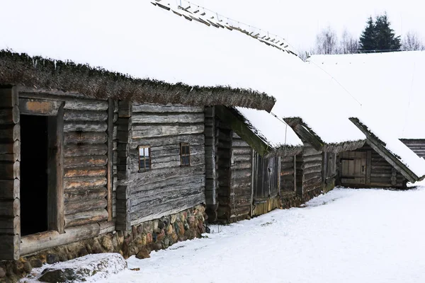 Rus kışı manzarası. Eski ahşap bir kulübe, sazdan çatılı ahşap bir ev. Karla kaplı terk edilmiş bir Rus köyü. Ahırlı ahşap ev. — Stok fotoğraf