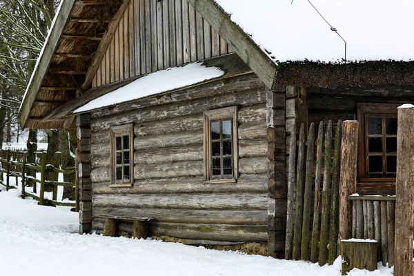 Зимний русский пейзаж. Старая деревянная хижина, бревенчатый дом с соломенной крышей. Заброшенная русская деревня, покрытая снегом. Деревянный дом с сараем. — стоковое фото