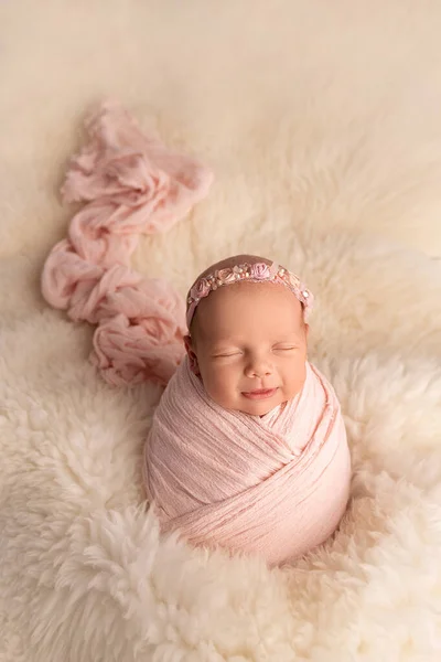 Спящая новорожденная девочка в первые дни жизни в розовом коконе с розовой повязкой на белом фоне. Студийная макрофотография, портрет новорожденного. Понятие женского счастья. — стоковое фото