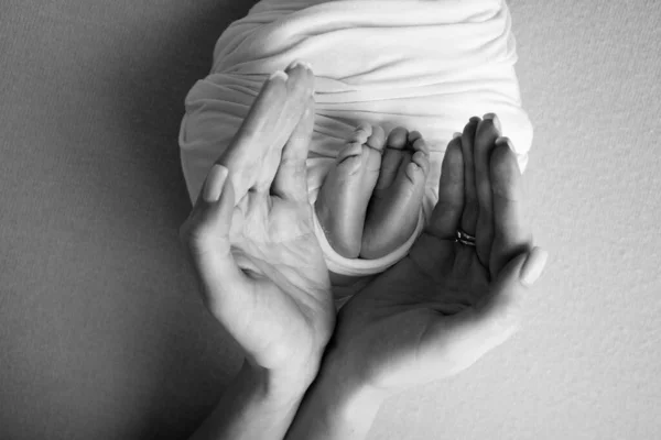 Les paumes du père, la mère tiennent le pied du nouveau-né. Pieds du nouveau-né sur les paumes des parents. Photographie d'un enfant orteils, talons et pieds. Photo noir et blanc. — Photo