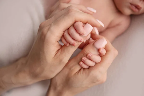 The hand of a newborn in the mothers hand. Mom and her child. Happy family concept. Beautiful concept image of motherhood.