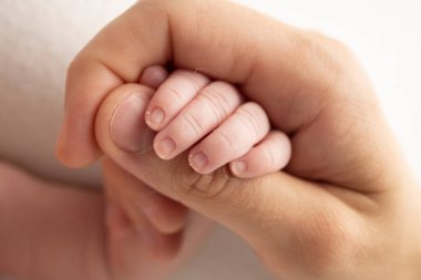 A newborn holds on to moms, dads finger. Hands of parents and baby close up. A child trusts and holds her tight. Tiny fingers of a newborn. The family is holding hands. Concepts of family and love. 