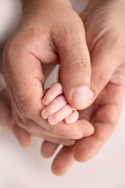 A newborn holds on to moms, dads finger. Hands of parents and baby close up. A child trusts and holds her tight. Tiny fingers of a newborn. The family is holding hands. Concepts of family and love. 