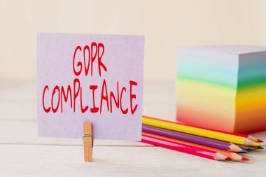 Gdpr Uyumluluğunu gösteren bir imza. Avrupa Birliği 'nin iş genel görünümü koruması ve mahremiyeti, Masaya yerleştirilmiş Boş Yapışkan Not Klipsi Renkli Kağıt Kalem Yığını.