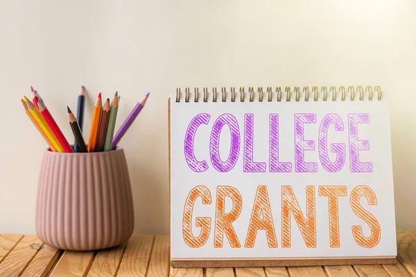 Text zeigt Inspiration College Grants. Auf Geldgeschenken geschriebenes Wort, um zu zeigen, wer eine höhere Bildung anstrebt Leeres Spiralheft Bunter Stapel Bleistifte im Container Auf dem Schreibtisch. — Stockfoto