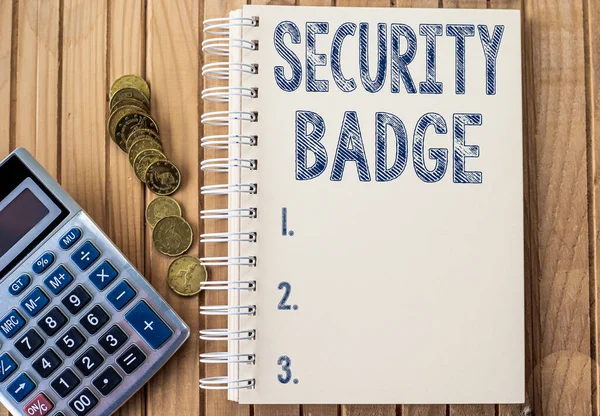 Text sign showing Security Badge. Business concept Credential used to gain accessed on the controlled area Plain Spiral Notebook With Pen Beside Calculator And Coins On Table.