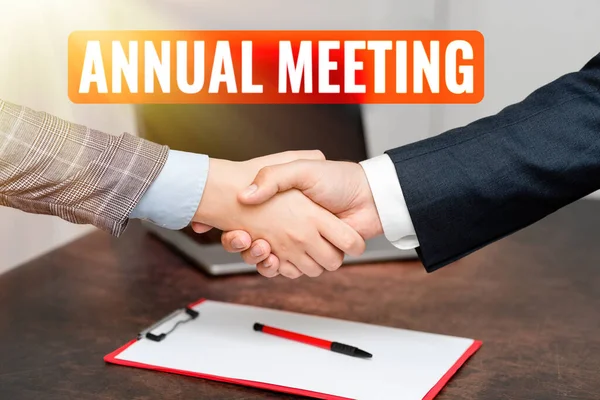 Sign displaying Annual Meeting. Business overview Yearly gathering of an organization interested shareholders Two Professional Well-Dressed Corporate Businessmen Handshake Indoors