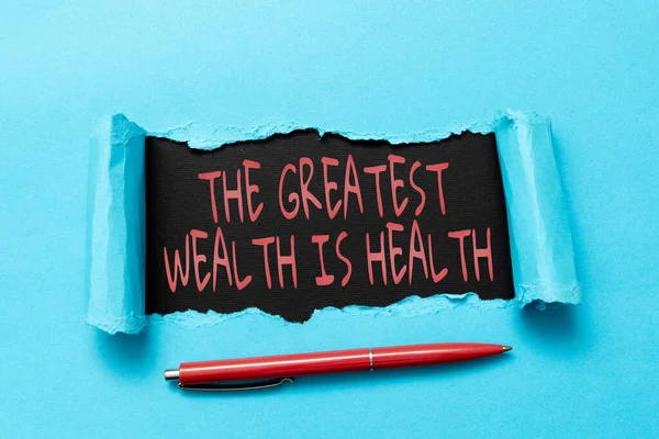 Ecrire un texte La plus grande richesse est la santé. Concept d'entreprise Beaucoup sacrifient leur argent juste pour être en bonne santé La larme sur la feuille révèle l'arrière-plan avec stylo à bord — Photo