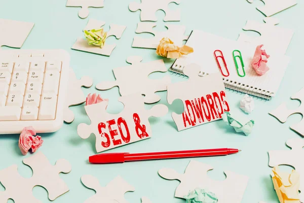 Conceptueel bijschrift Seo and Adwords. Concept betekent dat ze zijn belangrijkste tools componenten van Search Engine Marketing Building Een onafgewerkte witte puzzel patroon met ontbrekende laatste stuk — Stockfoto