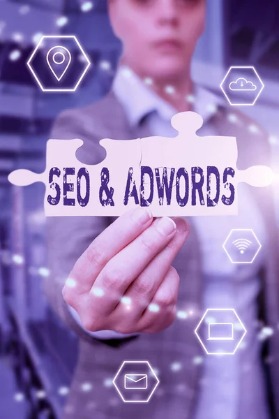 Υπογραφή εμφάνισης Seo And Adwords. Word Γράφτηκε για αυτά είναι τα κύρια συστατικά εργαλεία του μάρκετινγκ μηχανών αναζήτησης Business Woman Holding παζλ κομμάτι ξεκλειδώνοντας νέα φουτουριστική τεχνολογία. — Φωτογραφία Αρχείου