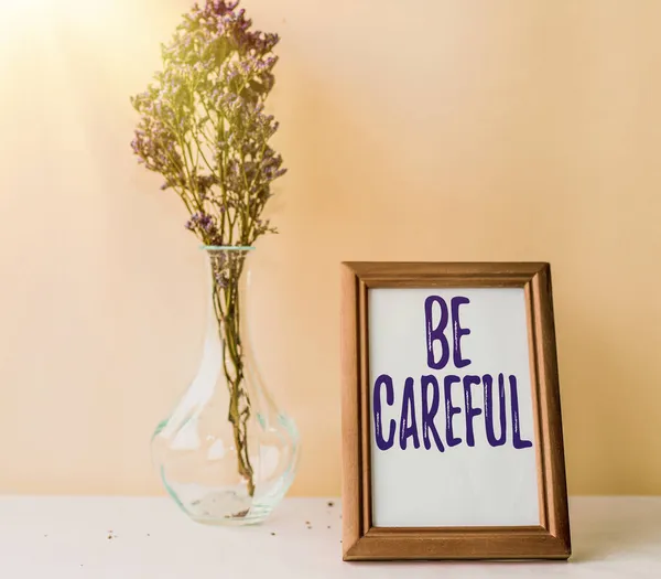 概念表示に注意してください。ビジネスの概要は、潜在的な危険性の事故や害を避けることを確認する花の花瓶が机の上に立って空の画像フレーム. — ストック写真