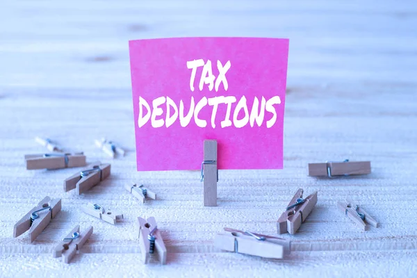 Text sign showing Tax Deductions. Concept meaning an amount or cost that subtracted from someone s is income Piece Of Blank Square Note Surrounded By Laundry Clips Showing New Idea. — Stock Photo, Image