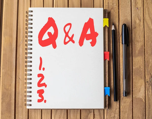 Escrever exibindo texto Q e A. Palavra Escrito em que a pessoa faz perguntas e outro responde-lhes em branco aberto espiral Notebook com canetas difrentes colocadas na mesa. — Fotografia de Stock