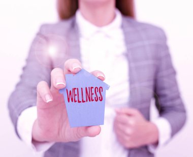Text sign showing Wellness. Internet Concept state of being in good health especially as actively pursued goal A Young Lady Businesswoman Holding Presenting Home In Business Outfit clipart