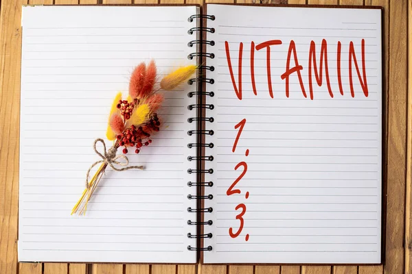 Rukopis Vitamin. Internet Koncepce skupina organických sloučenin, které jsou nezbytné pro normální růst Otevřít zápisník s barevným květem navrchu a umístěn na dřevěné desce — Stock fotografie