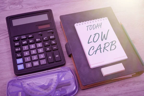 Text sign showing Low Carb. Word for Restrict carbohydrate consumption Weight loss management diet Blank Notebook Page With A Calculator And Geometric Stationery Over Table.