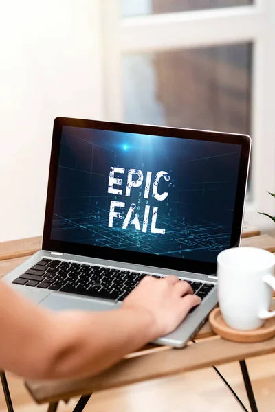 Handschrift Zeichen Epic Fail. Konzeptfoto ein spektakulärer peinlicher Fehler Demütigende Situation Hand ruht auf Laptop von Tisch neben Cup arbeiten von zu Hause aus. — Stockfoto