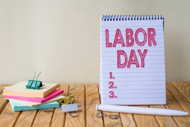 İşçi bayramını gösteren bir mesaj. İşletme konsepti işçilerin başarılarını kutlamak için yıllık bir bayram. Boş Spiral Not Defteri ve Kalem Yığını Yanında Yapışkan Notlar.